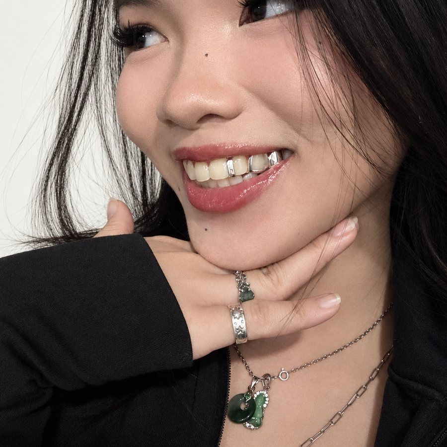 Khách cười để lộ hàng răng trên đeo grillz bạc kiểu viền hở, đeo kèm nhẫn và mặt dây ngọc bích